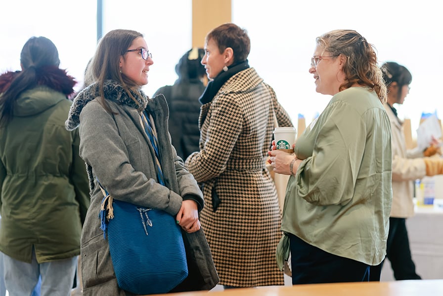 Two women talk at a gathering of community members