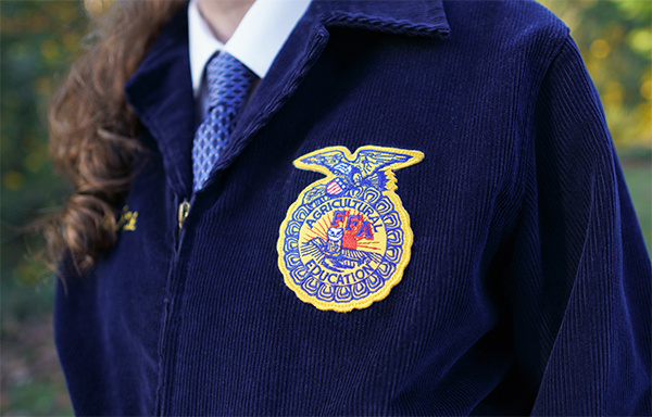 A Future Farmer of America (FFA) student stands wearing their jacket.