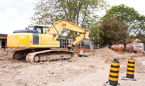 An excavator sits outside a school building construction site