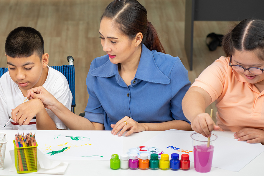 Students with disabilities take part in an art class with a teacher.